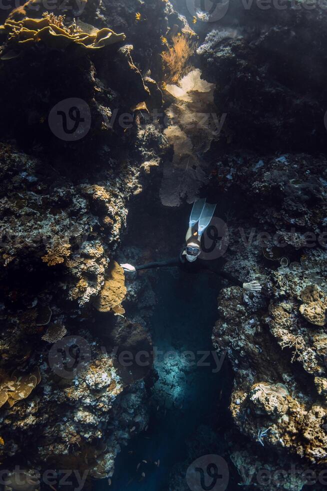 Female freediver emerges from underwater cave in ocean photo