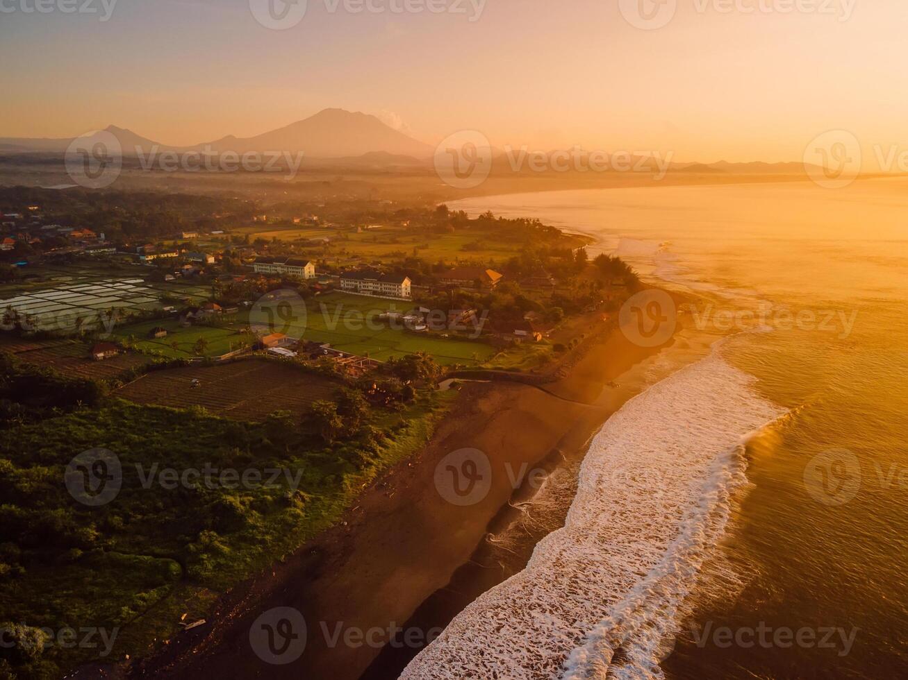 Drone view of beach coastline with Agung volcano with warm sunrise tones and ocean in Bali photo