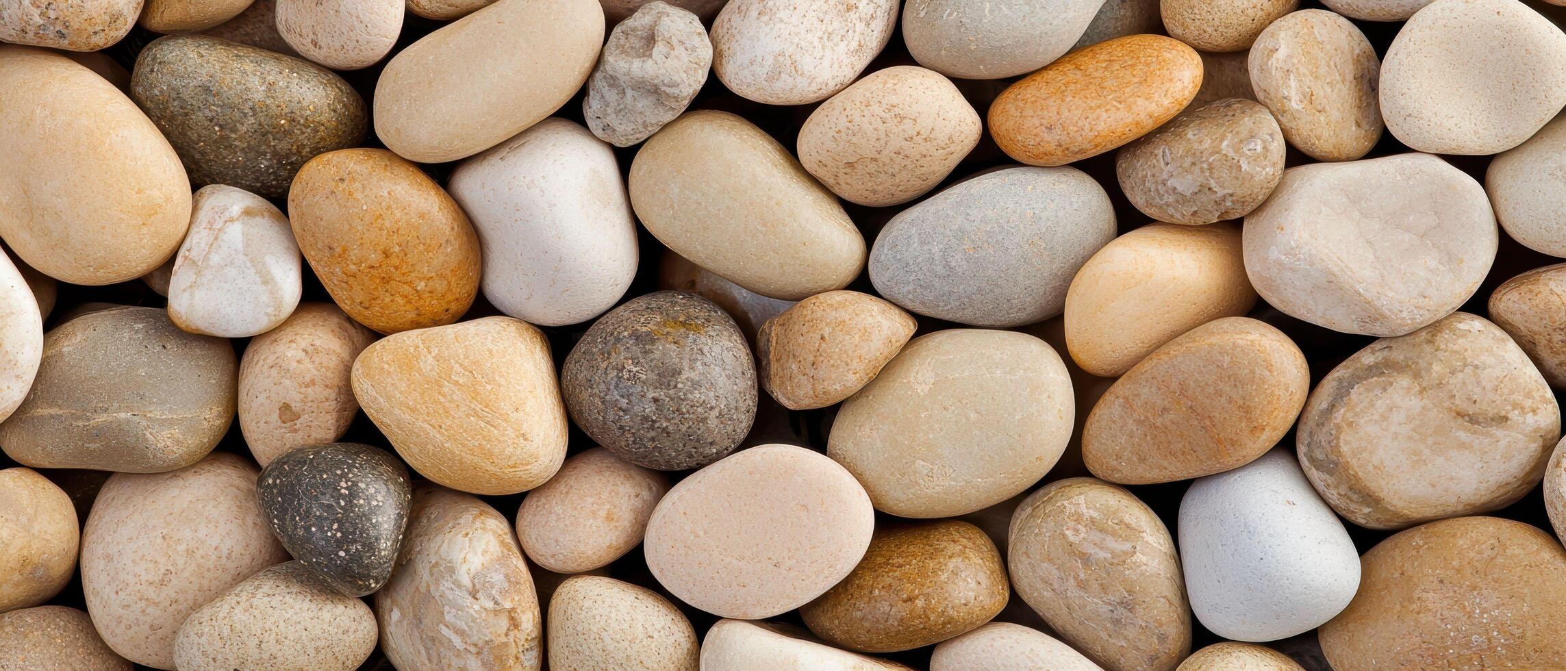 Mixed river pebbles close up showing various sizes and colors of smooth, rounded stones. The earthy tones and polished surfaces create a natural and organic background. photo