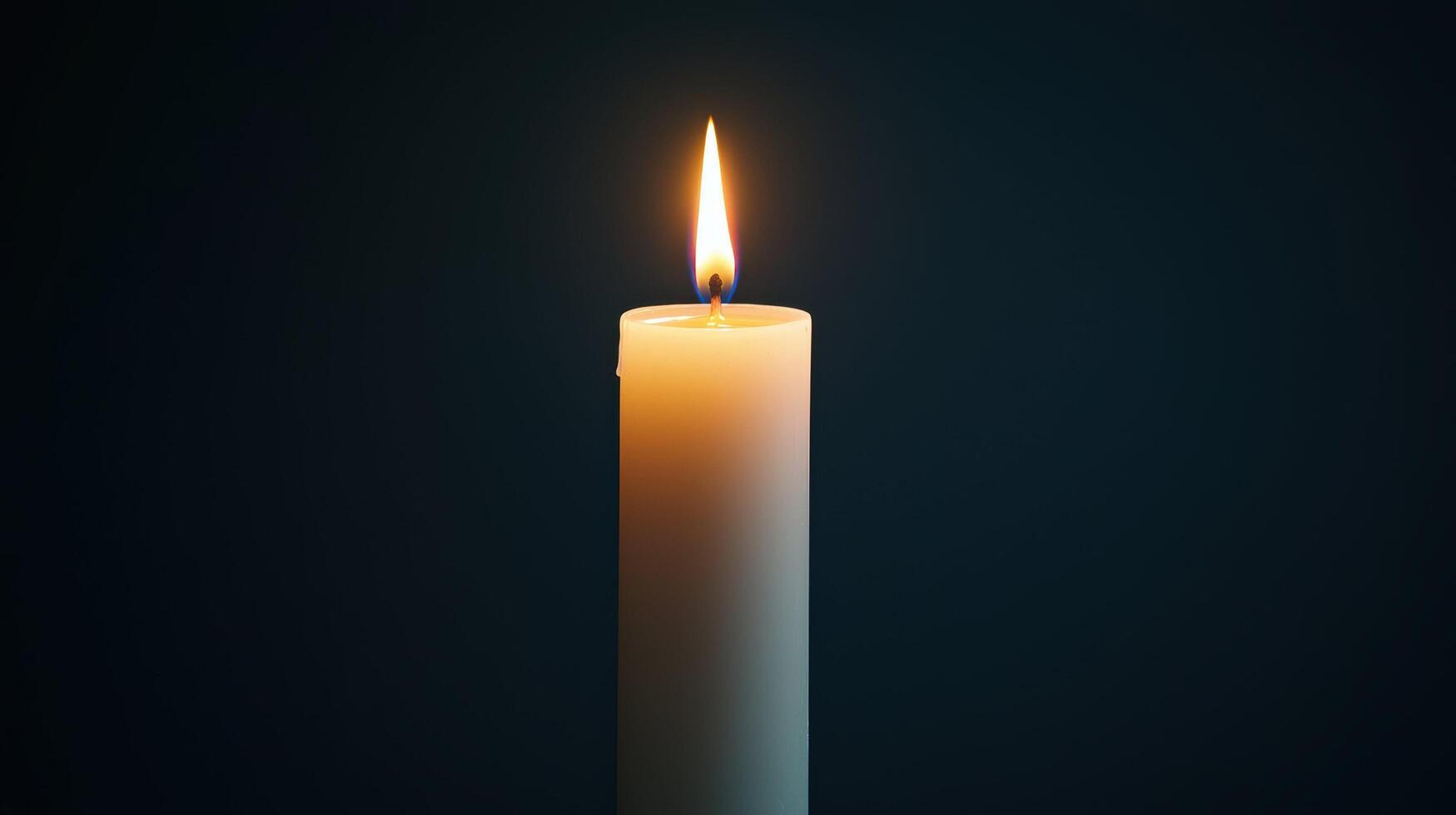 Single burning candle with a dark background. The warm glow of the flame creates a peaceful and reflective atmosphere, symbolizing hope, remembrance, spirituality, and solitude. photo