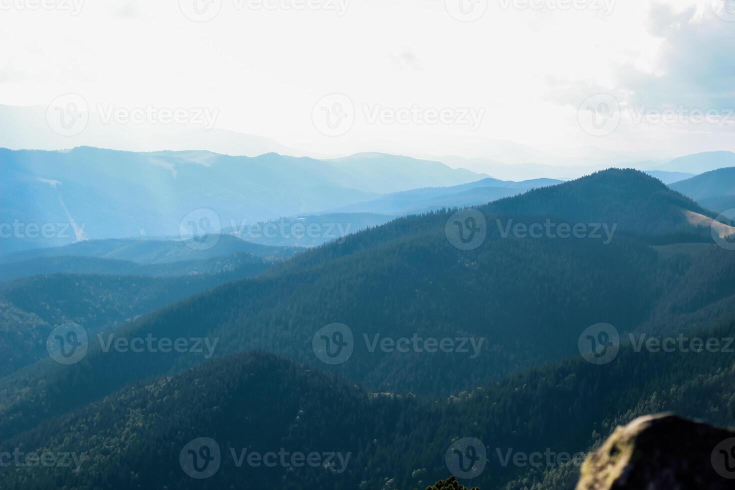 Mountains blanket the horizon under a cloudy sky at midday photo