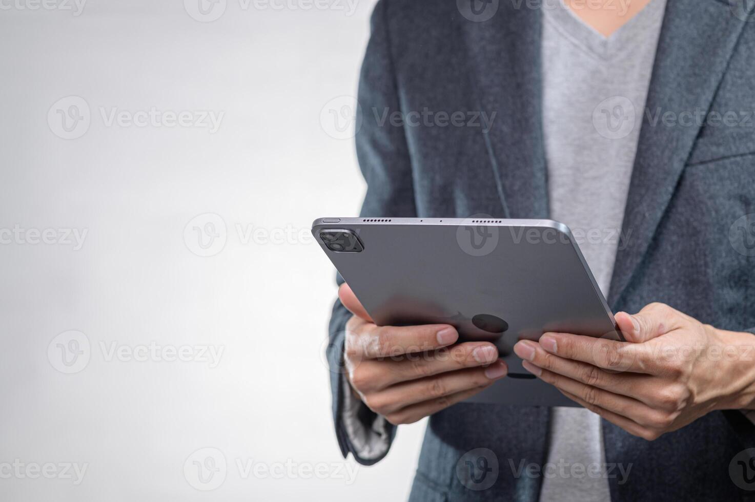Hands Holding Modern Tablet in Professional Attire Against Neutral Background photo