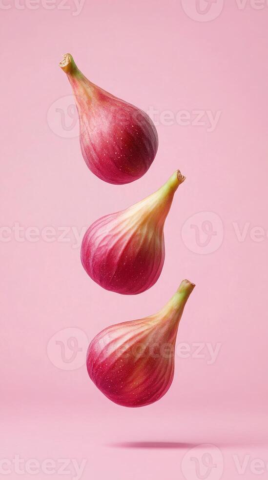Levitating hot pink figs create a surreal minimalist composition against a soft pink background photo