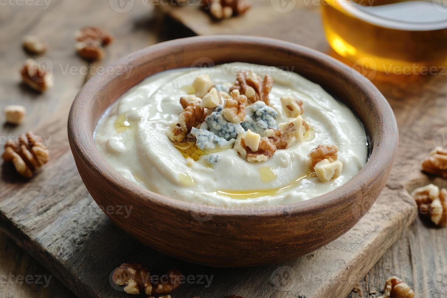 Cheese dip with Gorgonzola topped with nuts and olive oil on a rustic wooden board photo