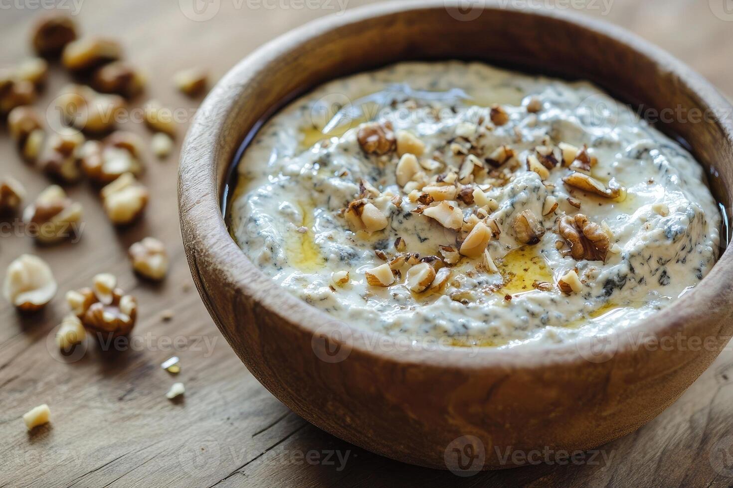 Delicious gorgonzola dip garnished with assorted nuts and a touch of honey on rustic wooden surface photo