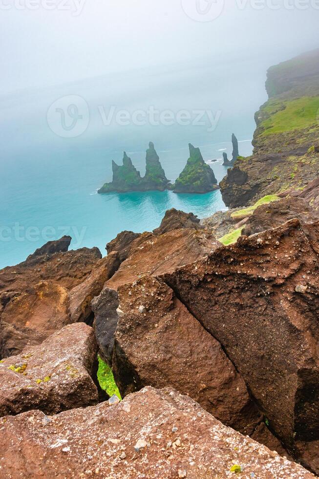 Cover page with basalt stacks Reynisdrangar, rocky cliffs and black sand beach at Vik town, Iceland, at summer sunny day and dramatic sky. photo