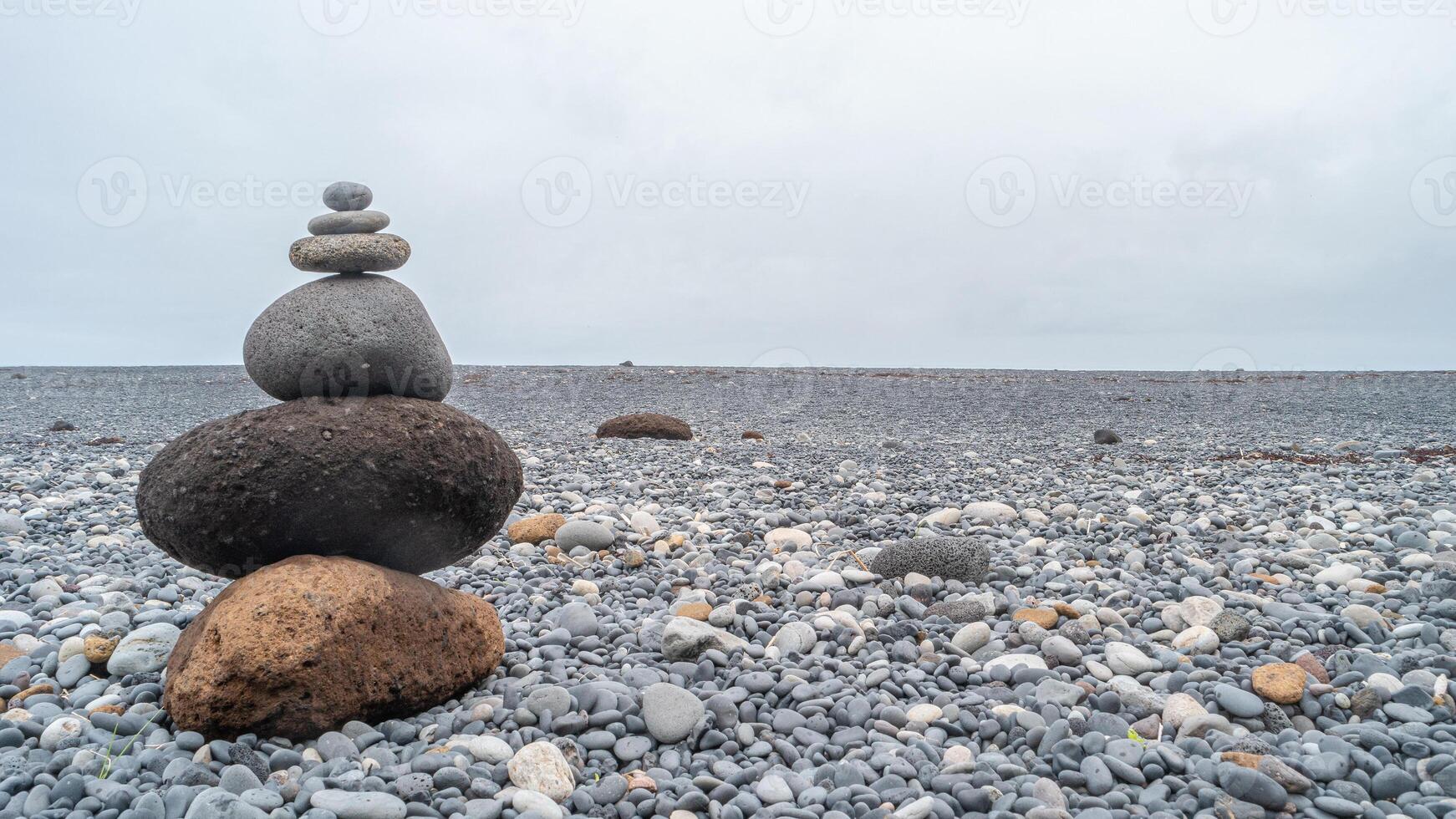 View of a pyramid made of stack of round stones put together at each other at stony gravel beach seacoast with copy space photo