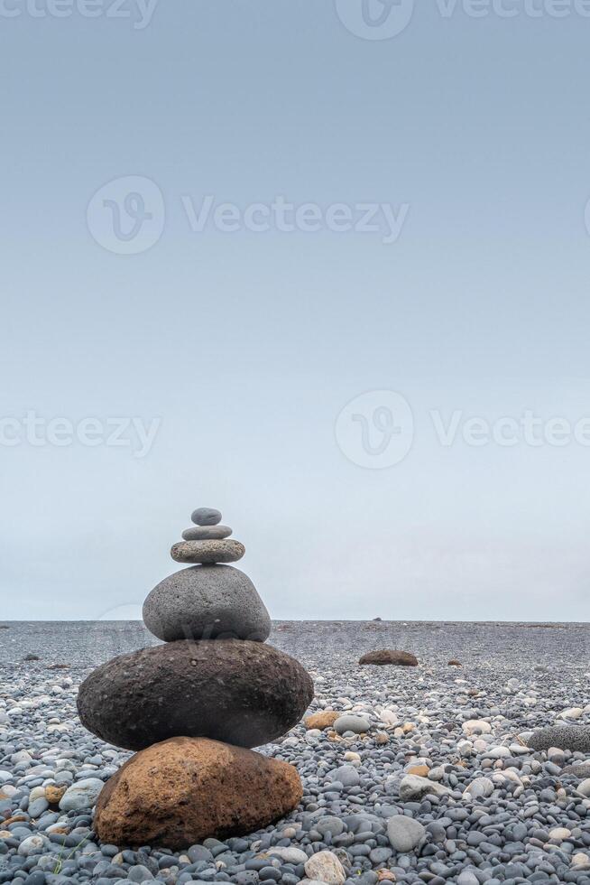 Cover page with view of a pyramid made of stack of round stones put together at each other at gravel beach seacoast copy space photo