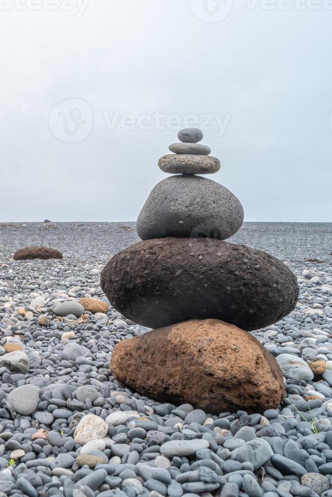 View of a pyramid made of stack of round stones put together at each other at stony gravel beach seacoast photo