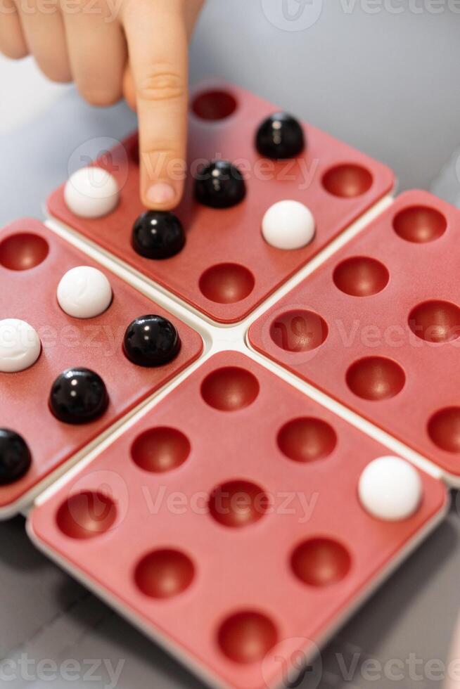 Family Game Time. A fun tabletop game brings together children and their friends, as they place marbles on the board. It's a moment of joy, strategy, and friendship. photo
