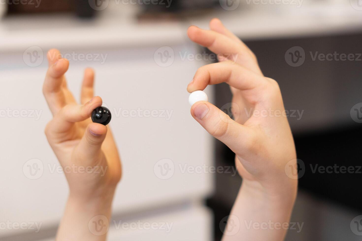 A hand holding black marbles hovers over the game board, ready to make the next strategic move. The player carefully plans each placement, aiming to outsmart the opponent. photo