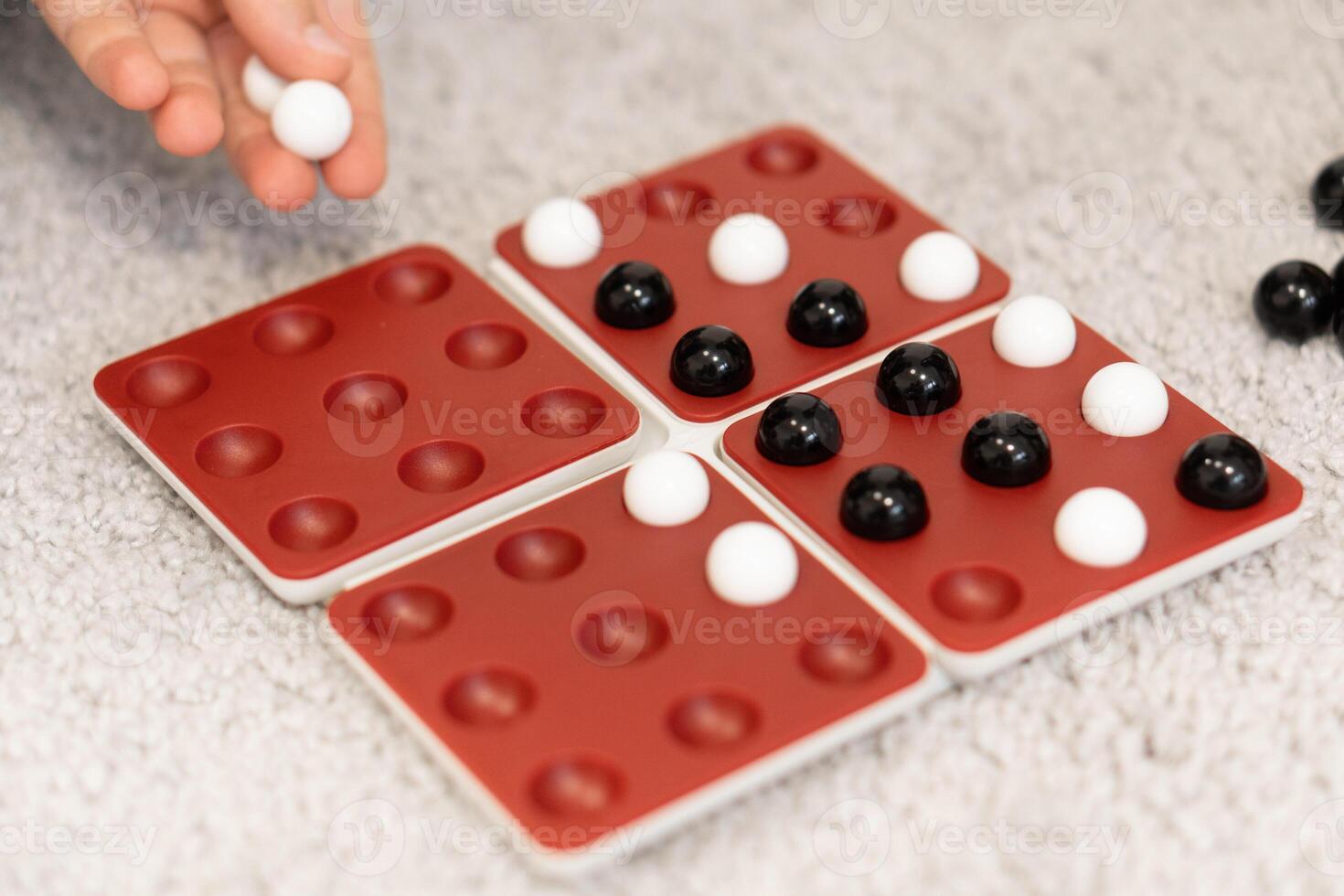 Kids take turns placing black and white marbles on the board, each move carefully planned. The game brings joy and challenges as they strategize to win. photo