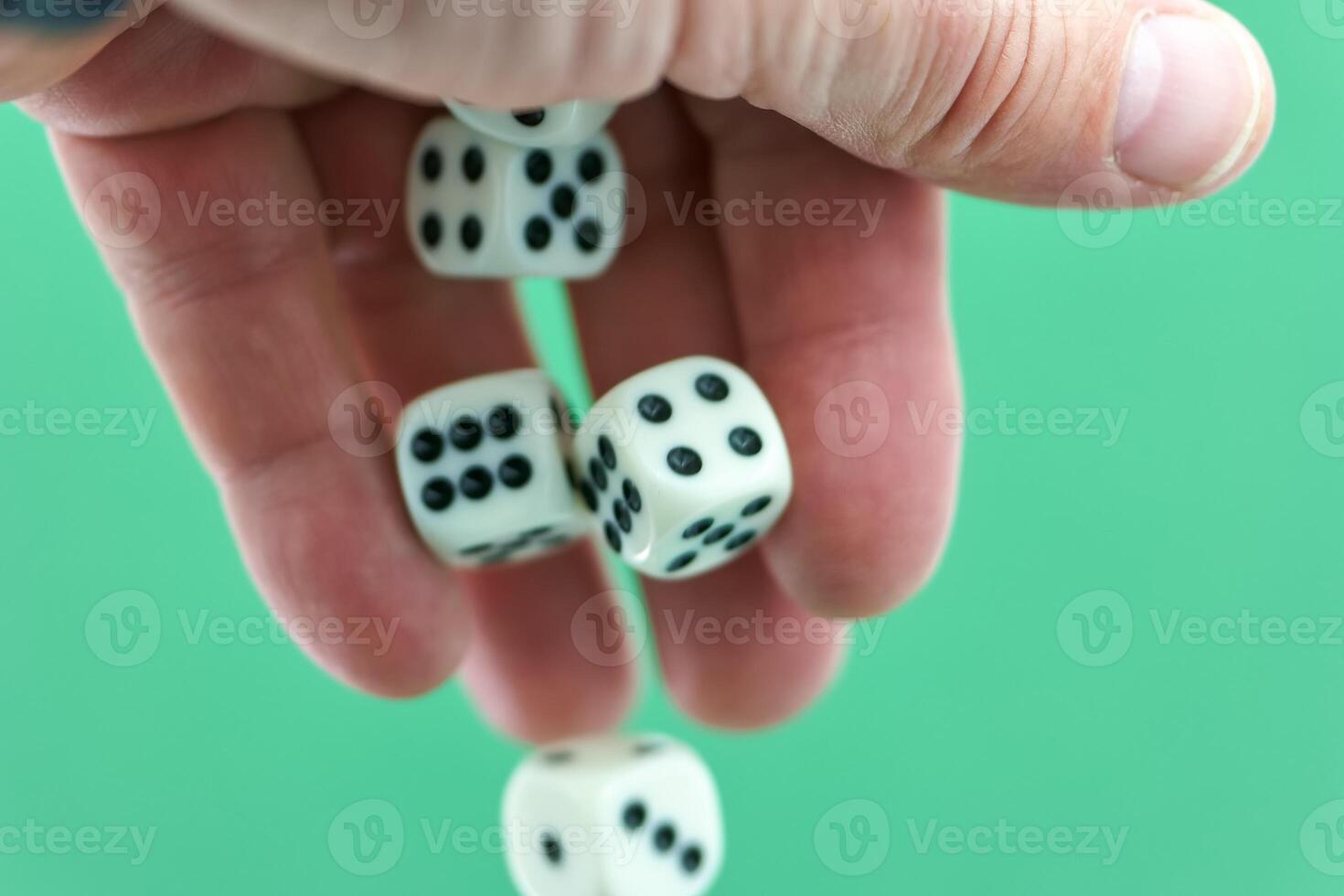 Hand dropping white dice with black dots on a green background d photo