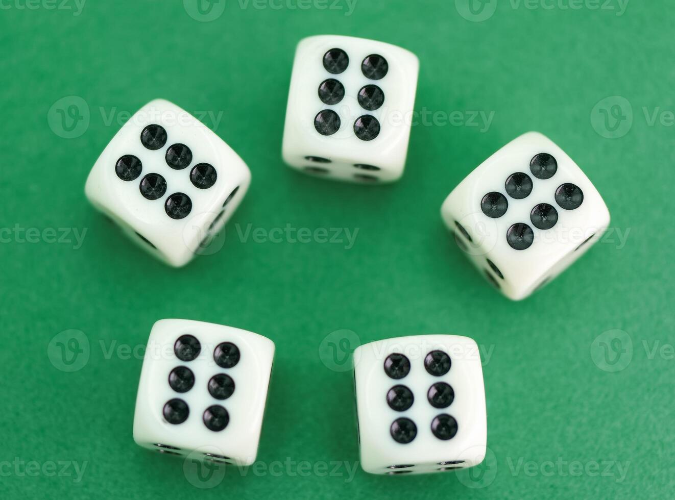 Five white dice showing various numbers on a green background re photo
