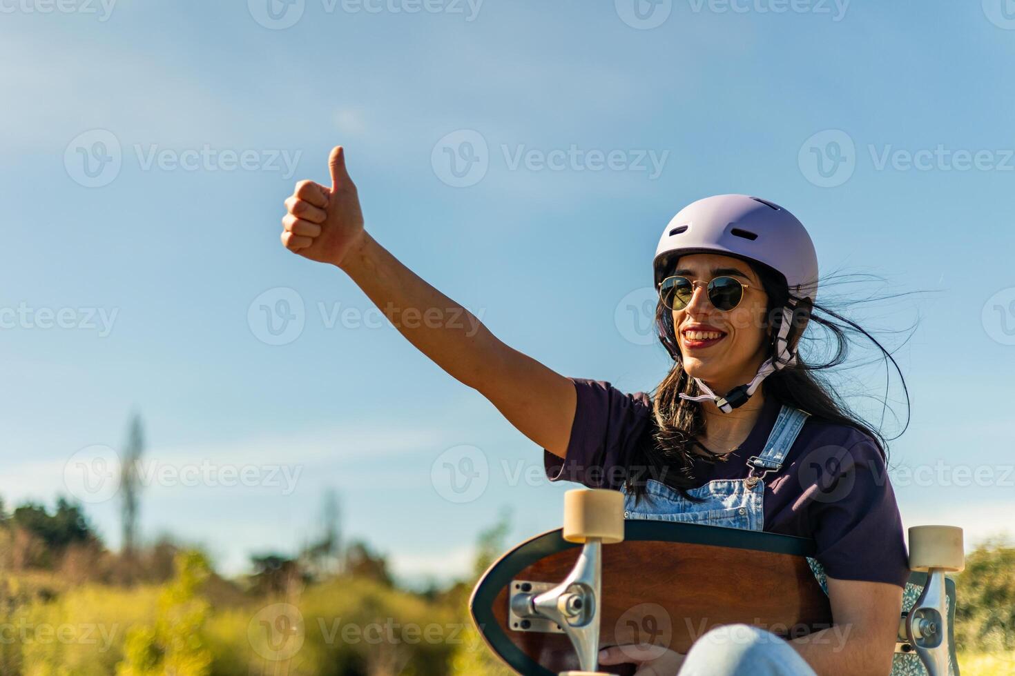 Happy latin skater gesturing thumbs up holding surfskate in pump track photo