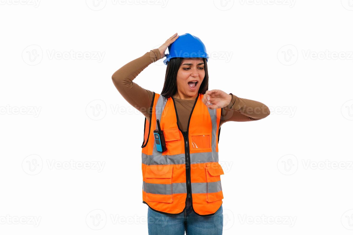 Stressed Latina construction worker checking time and touching helmet on white background photo