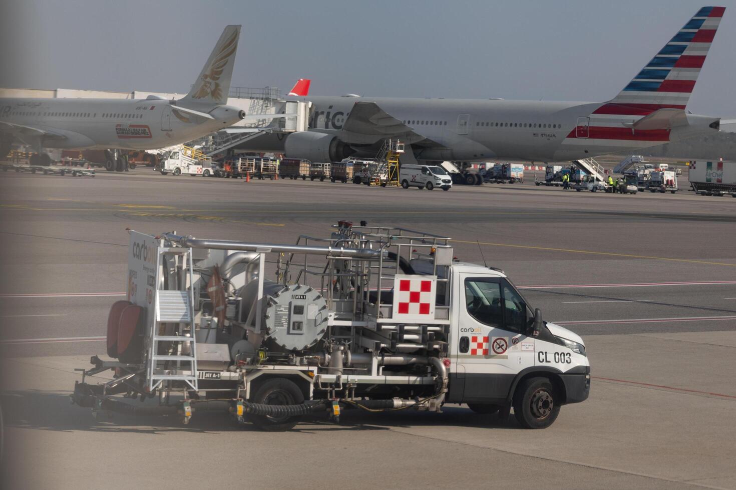 Milano, Italy - 8 March 2025 Airport runway with fuel service vehicle and commercial airplanes parked in Milan Malpensa Airport photo