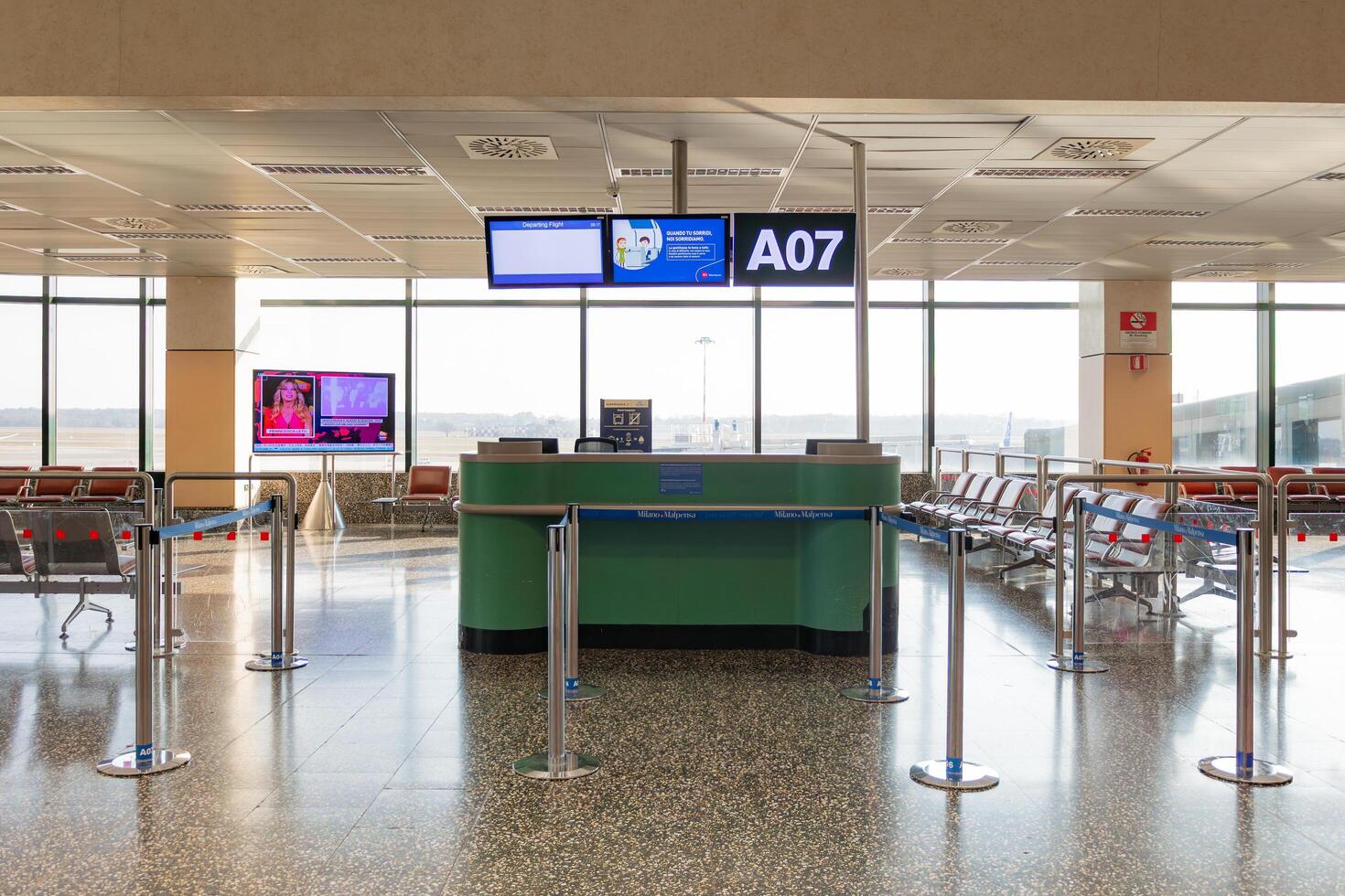 Milano, Italy - 8 March 2025 Empty airport gate a07 with seating and lcd screens at sunlit terminal in Milan Malpensa Airport photo
