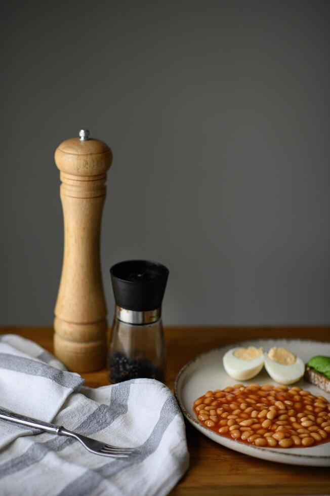 A simple yet elegant breakfast composition with a fried egg, tomato-braised white beans, and a crunchy toast topped with avocado and black salt. photo