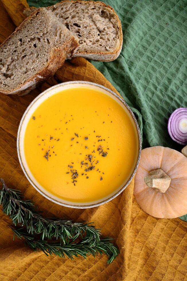 Warm autumn hues highlight a rich, creamy pumpkin soup served with rustic whole-grain sourdough. photo