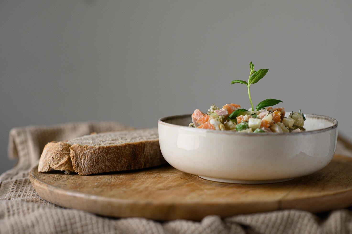 A hearty portion of Russian Olivier salad, perfectly paired with dark sourdough and placed on a plate. photo
