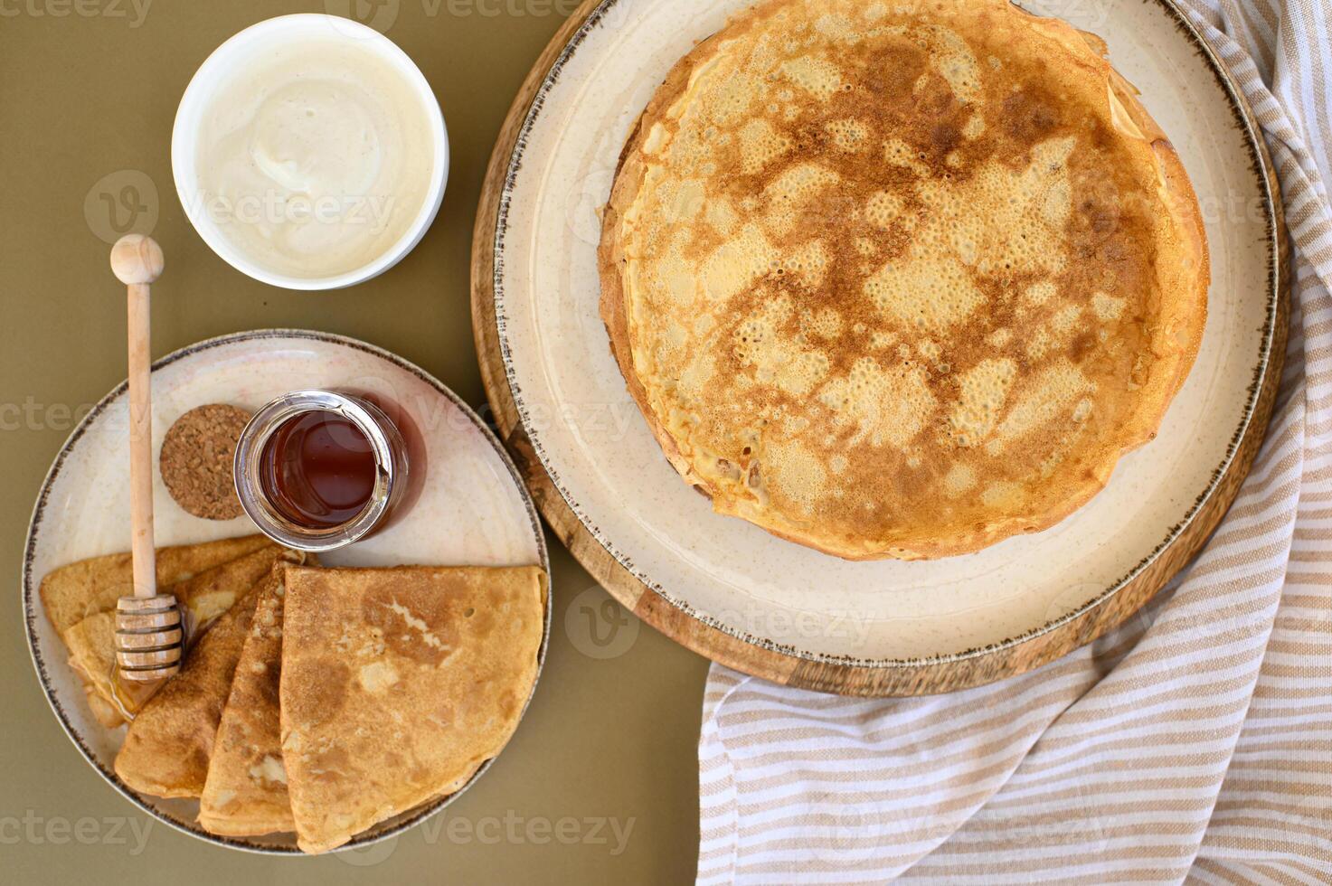 A stack of warm pancakes with a honey dipper resting on top, paired with rich sour cream, shot in a cozy, inviting atmosphere. photo