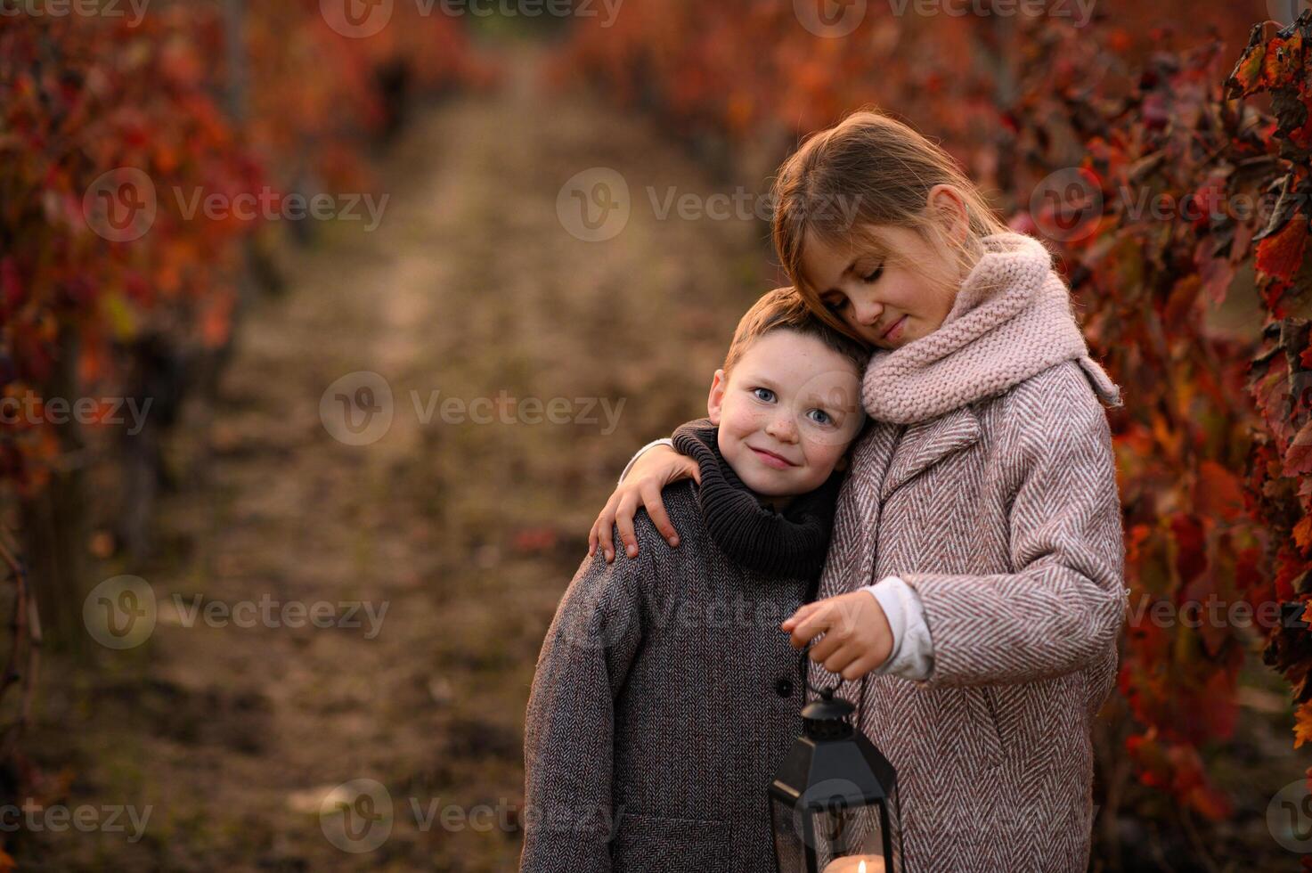 A close-up portrait of a boy and a girl wrapped in a warm embrace, their lantern casting a golden glow on their faces. photo