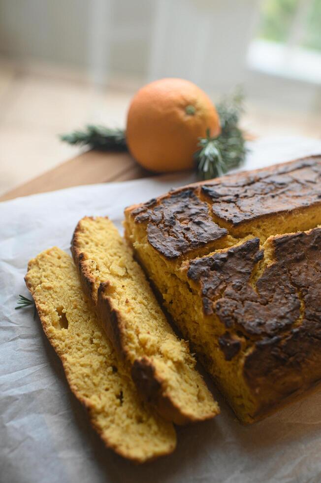 A homemade orange cake, with caramelized edges and a soft, fragrant center, is elegantly presented on a rustic wooden board, ready to be savored photo