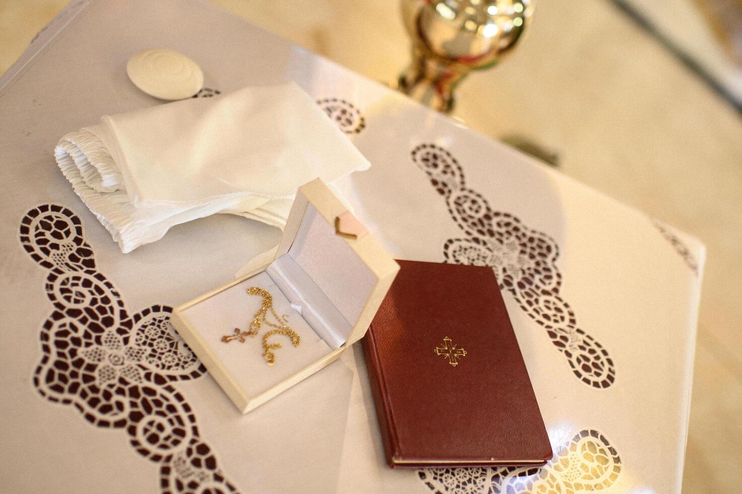 A delicate baptismal set, including a cross, a Bible, and ceremonial accessories, rests on a sacred altar inside a church. photo