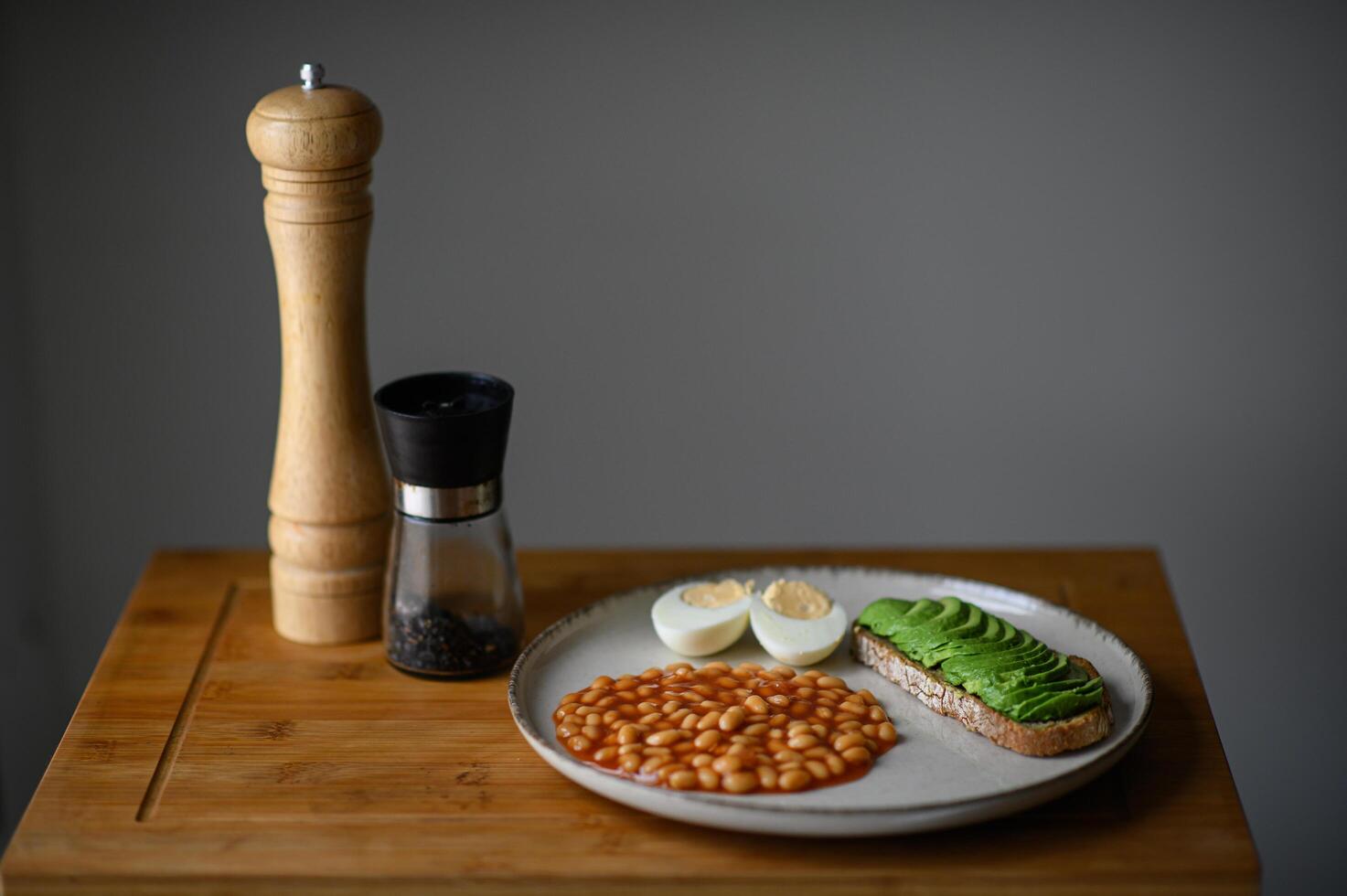 A rustic yet sophisticated morning meal with homemade white beans, a fried egg, and avocado toast seasoned with black salt. photo