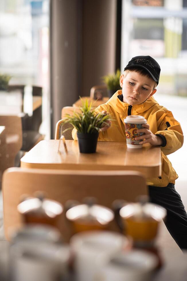 A peaceful morning young boy in a casual cap enjoys his coffee, immersed in his own thoughts. photo