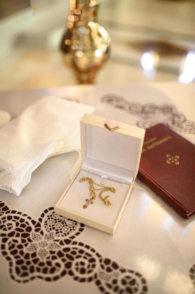 A golden cross, an open Bible, and elegant christening items are beautifully arranged in a church, symbolizing faith and devotion. photo