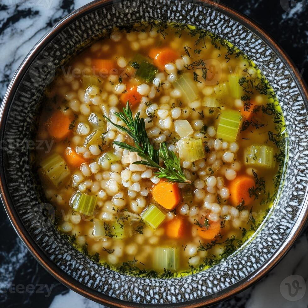 Steaming pearl barley soup garnished with fresh herbs and vegetables photo