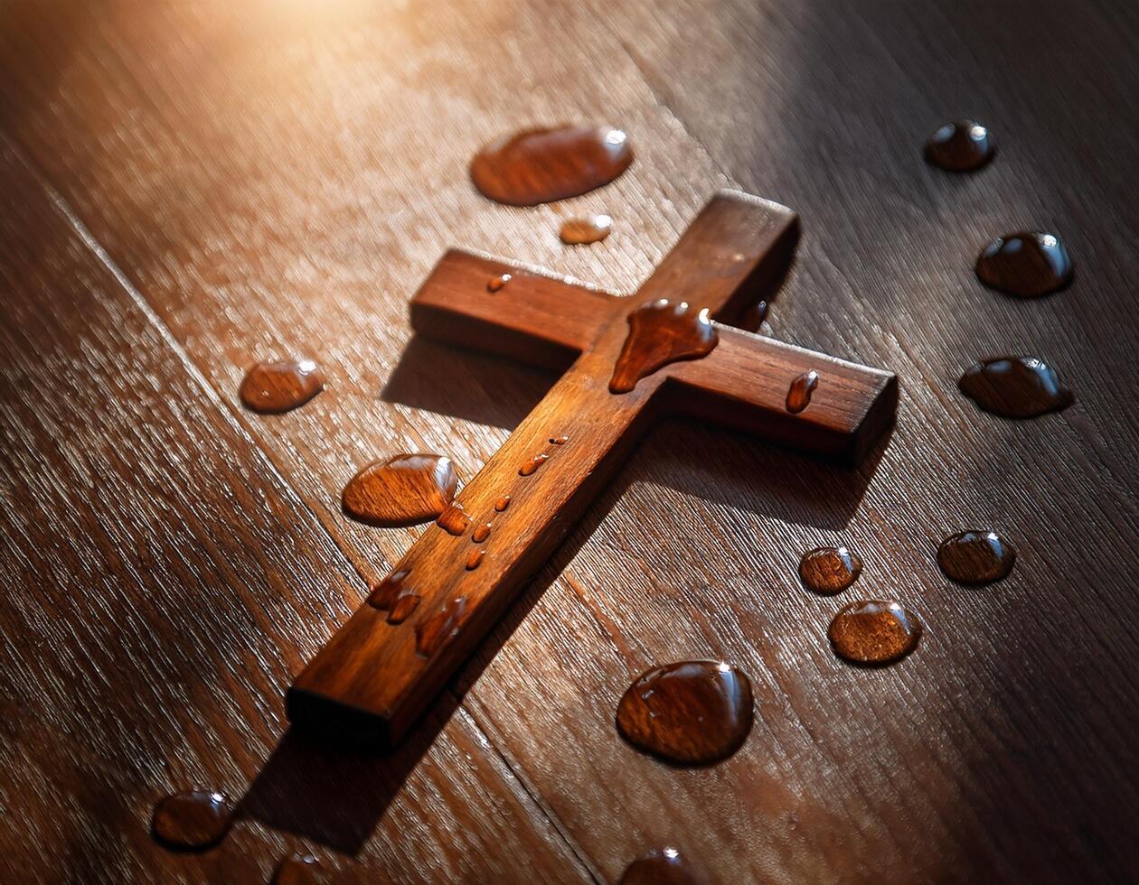 christian cross dropping on the wooden floor with drop of tears on it photo