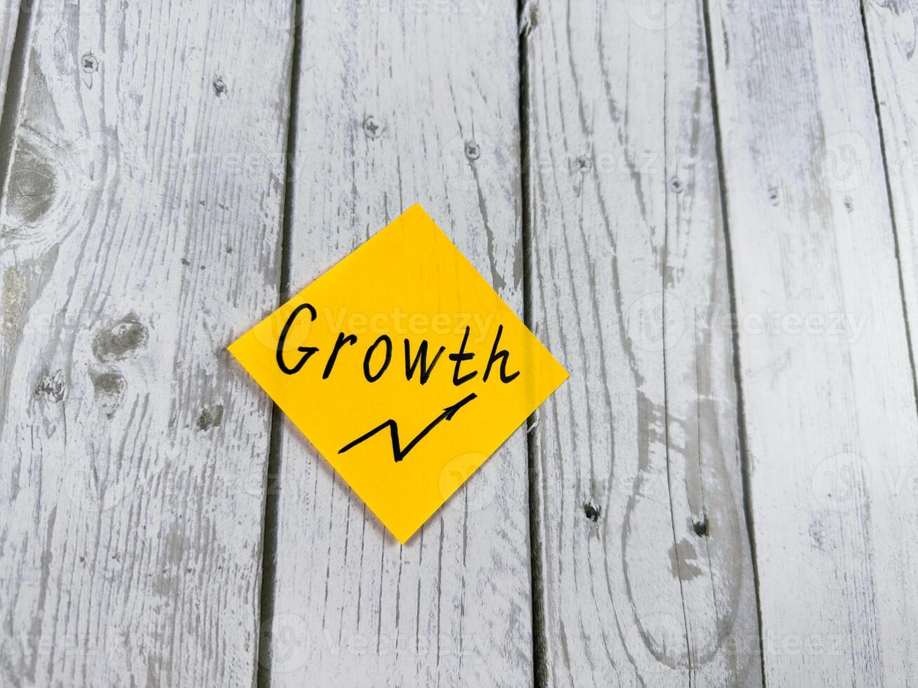 Sticky note featuring the word Growth with an upward arrow, set against a rustic textured wooden surface, symbolizing development, optimism, and the pursuit of personal and professional advancement photo