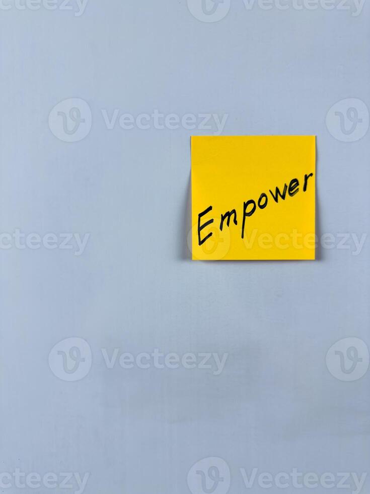 Sticky note with Empower written on it, affixed to a white background. This image represents strength and confidence, ideal for themes of empowerment and personal growth photo