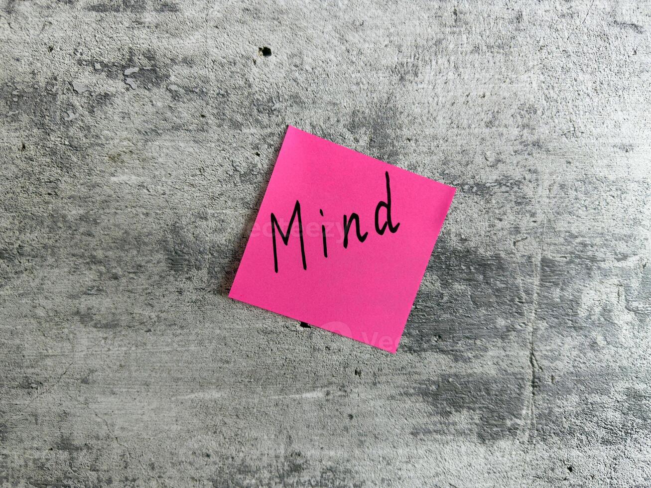 Vibrant pink sticky note with the word Mind displayed on a textured grey background, representing concepts of mental awareness, mindfulness, and personal reflection for growth and understanding photo