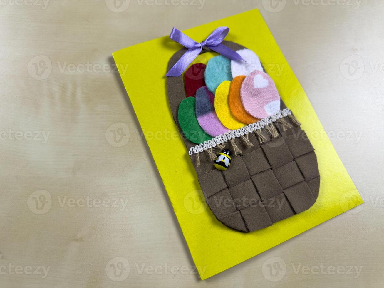 Vibrant handmade Easter card showcases woven basket filled with assorted felt eggs and charming bee. Perfect for sending heartfelt wishes and celebrating joyful spirit of Easter with loved ones photo