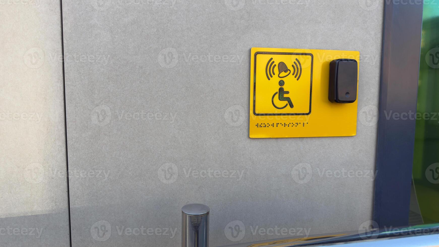 Disabled person sign with braille text and panel with button to call staff for assistance at entrance to building. Social problem of creating accessible areas for people with disabilities photo