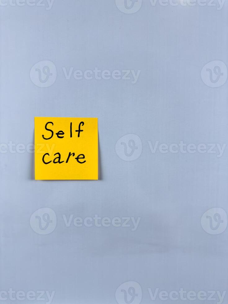 Sticky note with Self Care written on it, affixed to white background. This image represents well being and self love, ideal for themes of personal wellness and self care photo