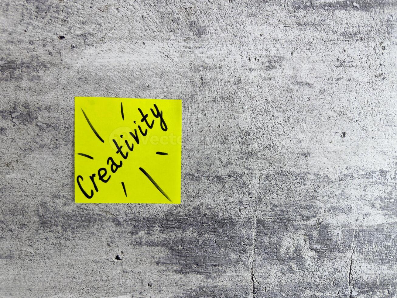 Bright yellow sticky note displaying the word Creativity with decorative elements on a textured grey background, symbolizing inspiration and the power of imaginative thinking photo