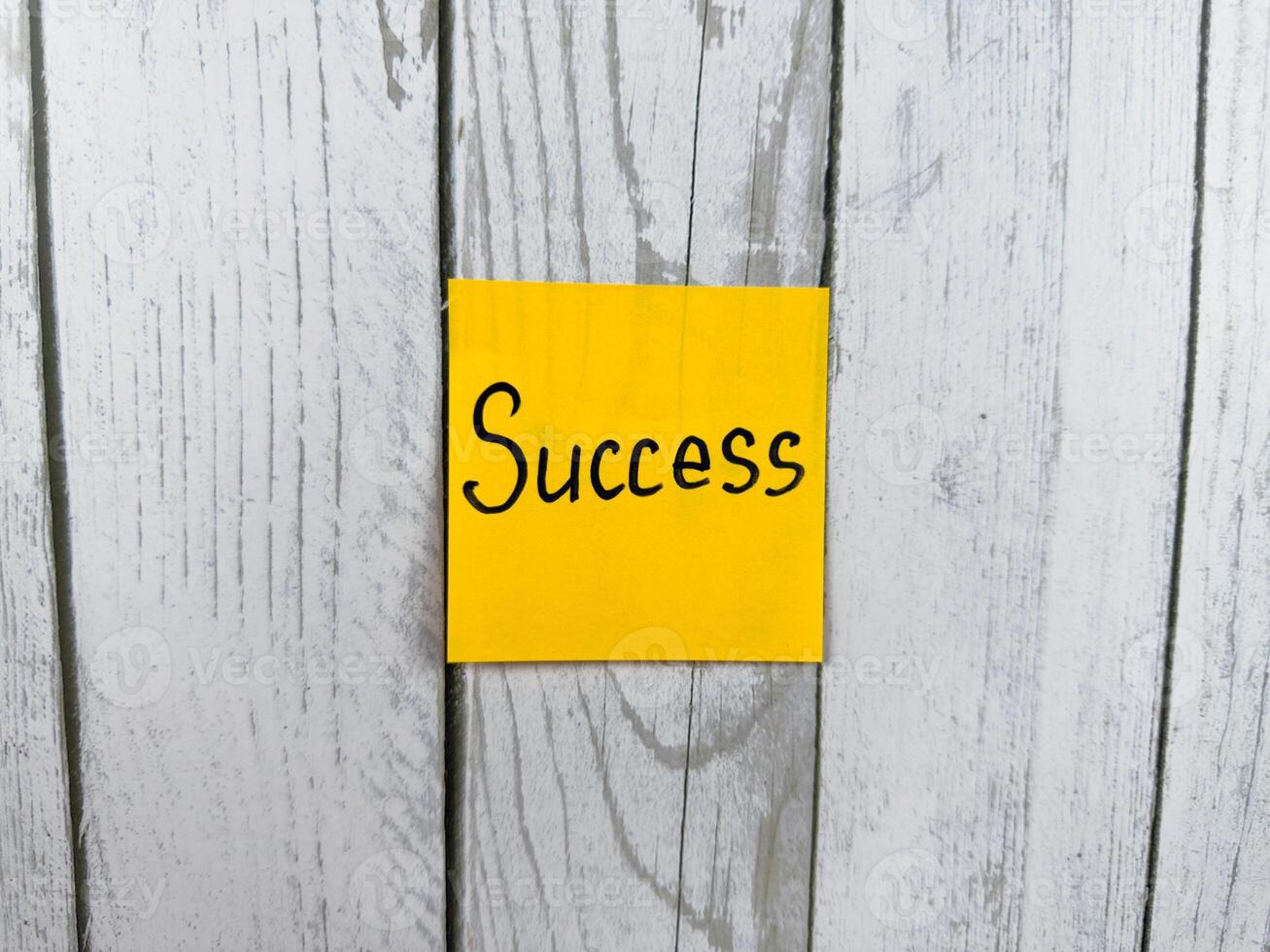 Bright sticky note displaying the word Success against a rustic textured wooden background, symbolizing achievement, personal growth, and the journey toward goals photo