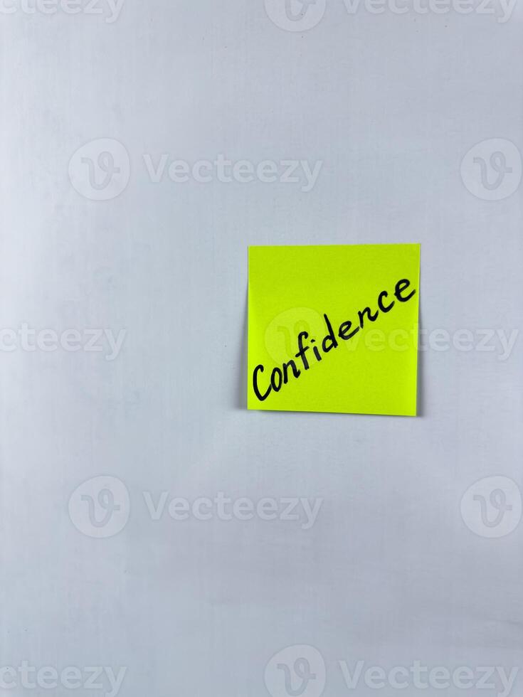 Sticky note with Confidence written on it, affixed to a white background. This image represents self assurance and trust, ideal for themes of confidence in life and professional settings photo
