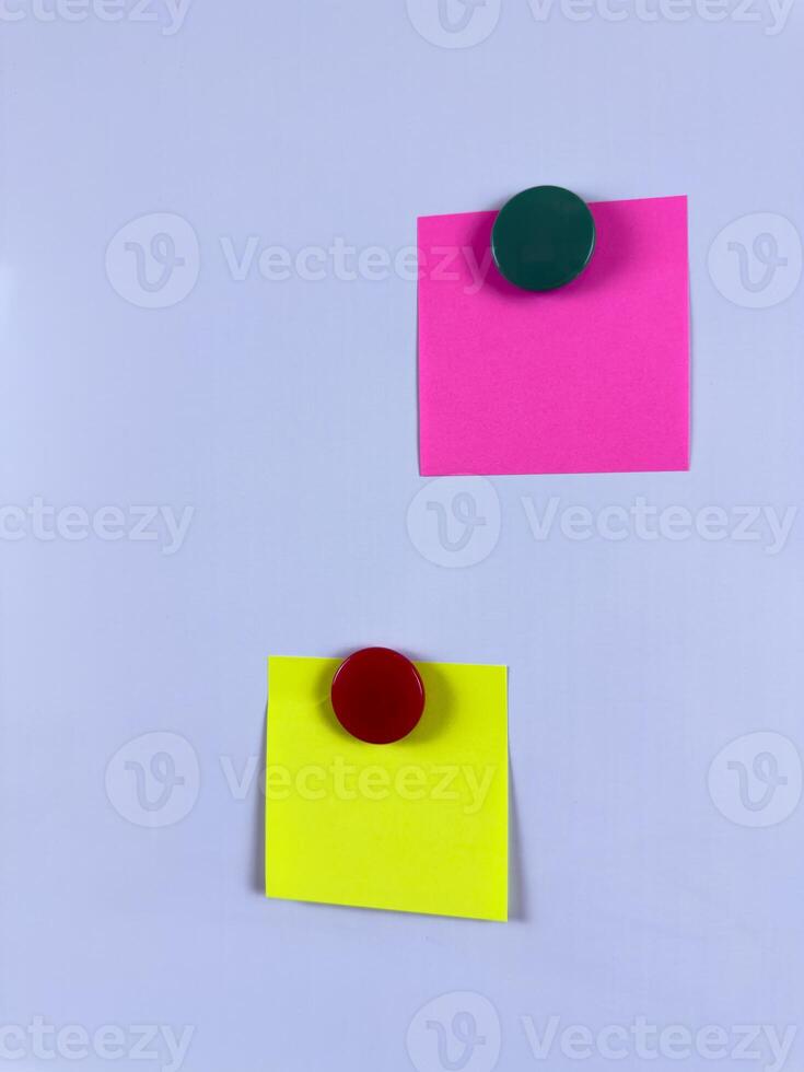 Pink and yellow sticky notes secured with magnets on a whiteboard ideal for reminders planning and organization in office school or home environments enhancing efficiency and creativity photo