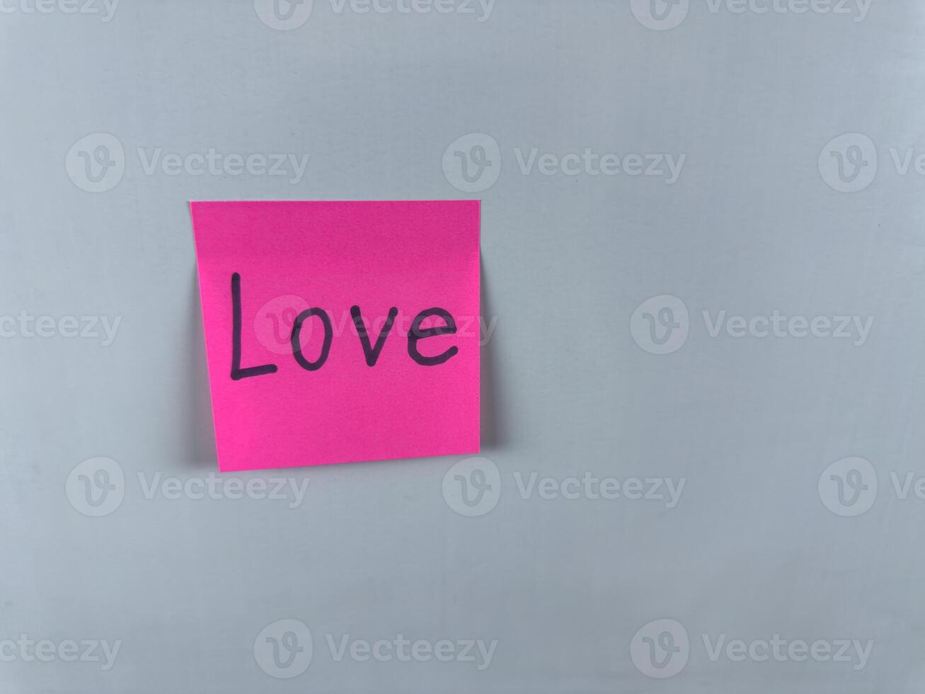 Sticky note with Love written on it, affixed to a white background. Photo represents the emotion of love and is ideal for conveying themes of romance, relationships, and personal connections