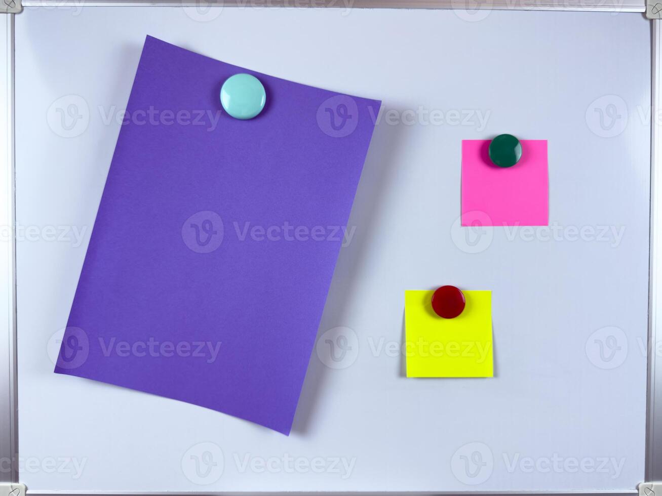 Vibrant paper notes in different colors attached to whiteboard with colorful magnets perfect for organizational and creative workspace themes photo