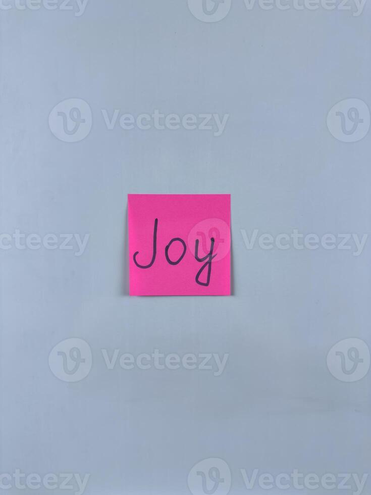 Sticky note with the word Joy written on it, placed on white background. Ideal for illustrating themes of happiness, positivity, and delight. Great for concept creation photo