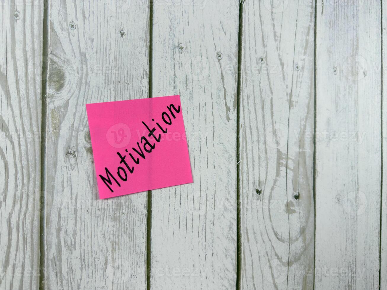 Sticky note with Motivation written on it, affixed to a white wooden board. Representing inspiration and drive, this image is perfect for concepts of personal growth and determination photo