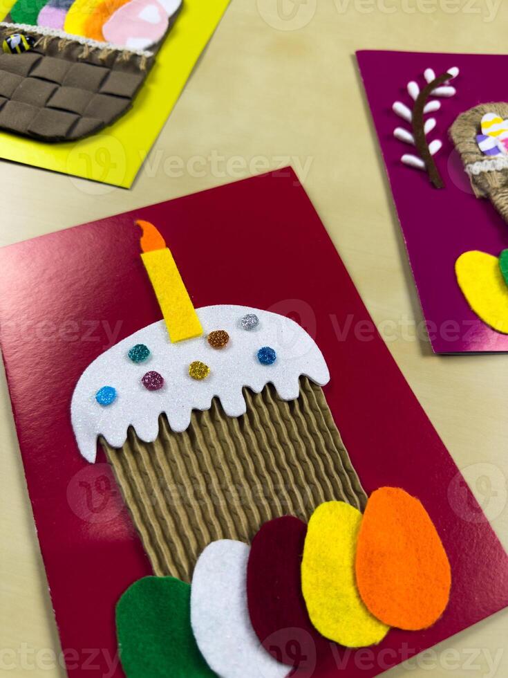 Whimsical handmade Easter card features decorated cake with candle, complemented by colorful felt eggs. Perfect for adding joyful touch to Easter celebrations and sending heartfelt wishes photo