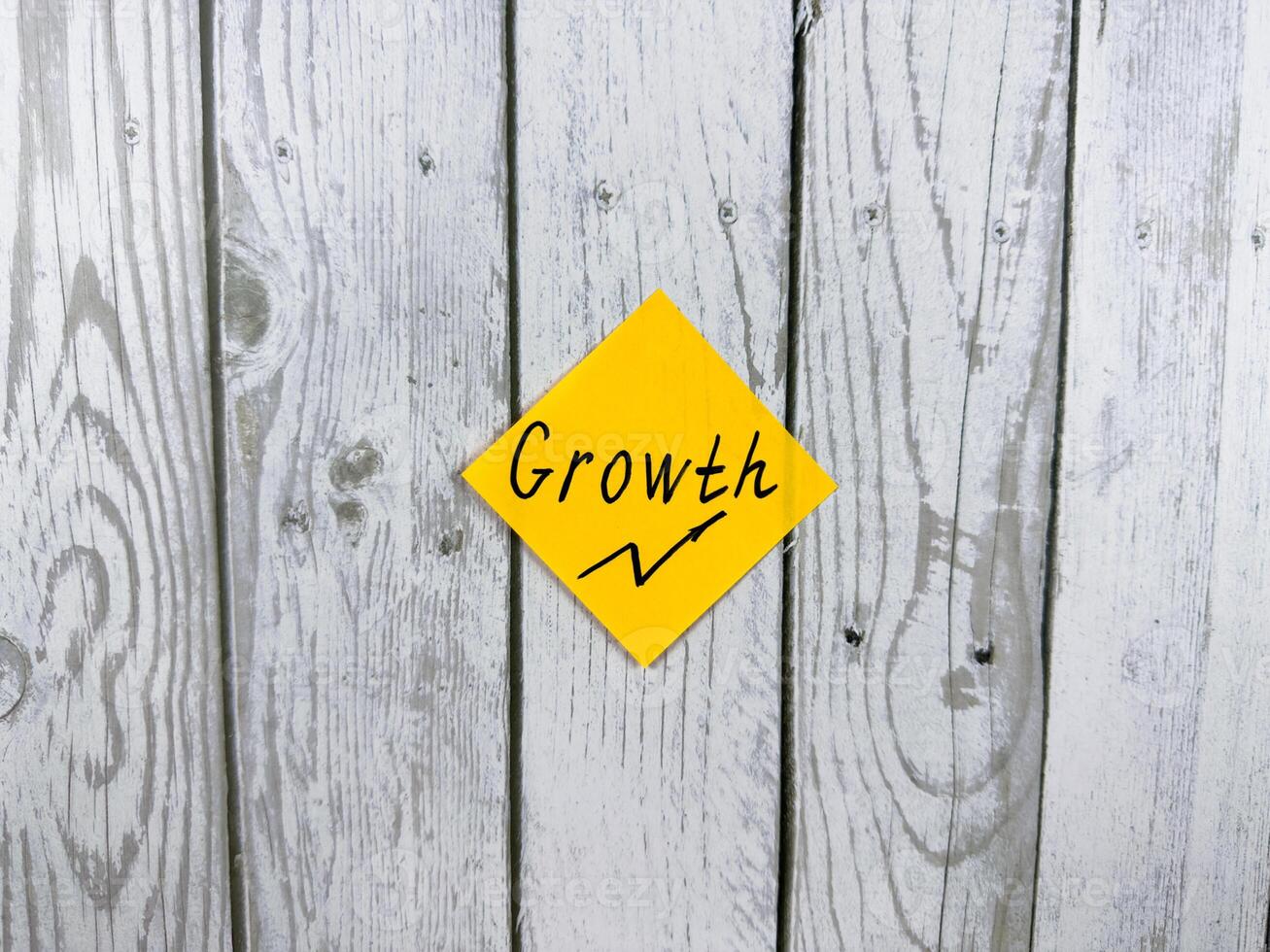 Bright sticky note displaying the word Growth, placed on textured wooden background, symbolizing personal development and progress in life photo